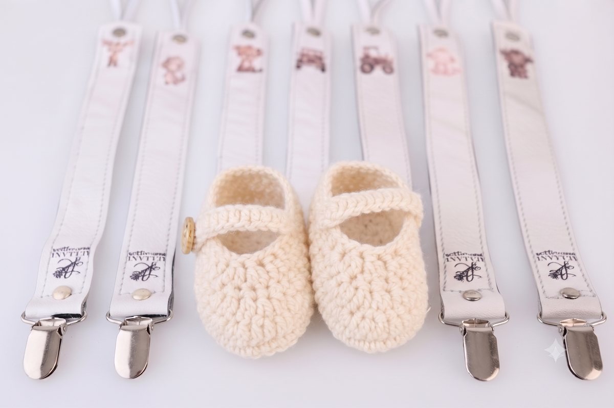 Crocheted baby booties beside white suspenders - part of our premium Accessories collection.