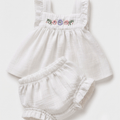 A baby girl's two-piece outfit consisting of a white sleeveless dress with floral embroidery on the chest and matching white ruffled bloomers, laid flat on a light background.