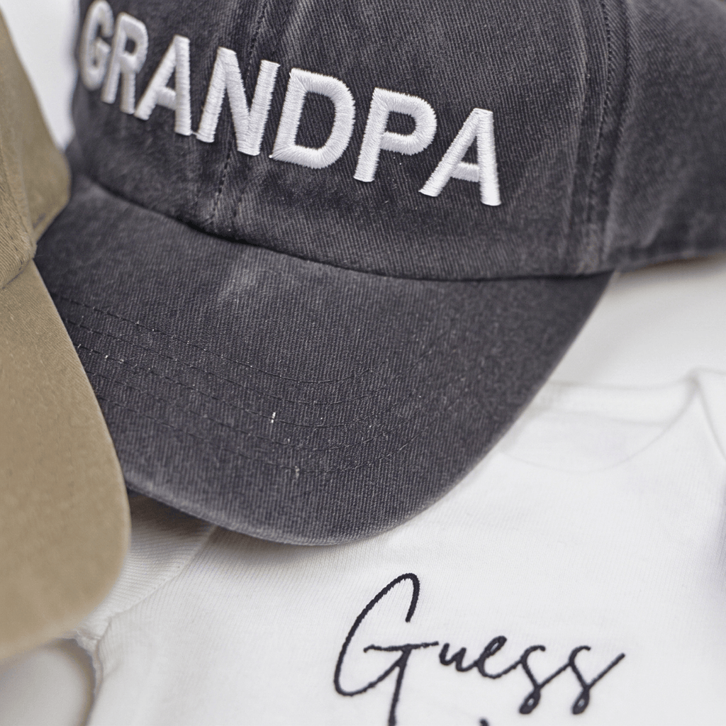 Guess What New Parents Announcement Cap Gift Box featuring a Grandpa cap and a baby onesie.