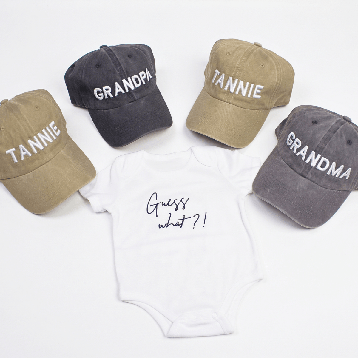 Guess What New Parents Announcement Cap Gift Box featuring caps for grandparents and a onesie with Guess what?! design.