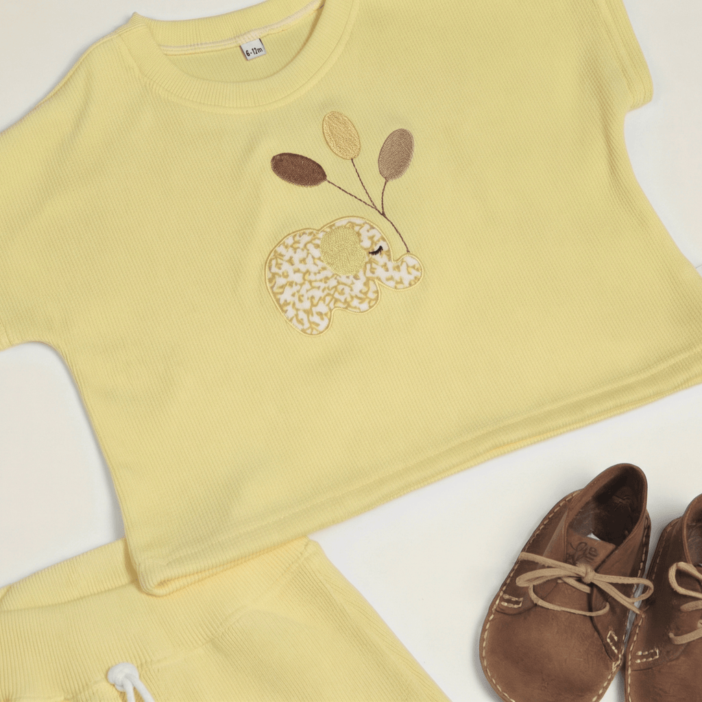 safari play cotton set for baby featuring yellow T-shirt with embroidered elephant and balloon details, styled with shoes.